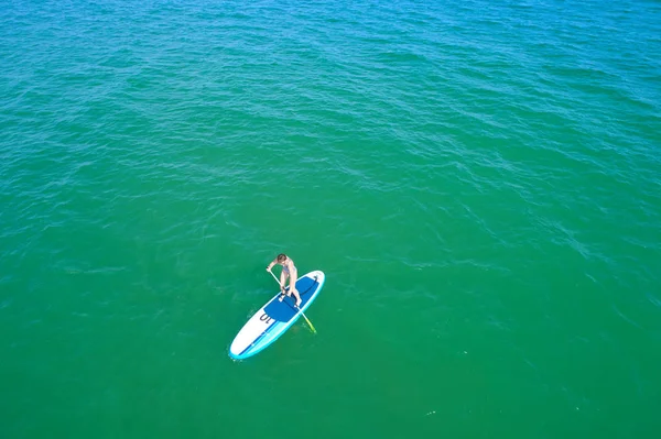 Aerial drone birds eye view of young woman exercising sup board in turquoise tropical clear waters — Stock Photo, Image