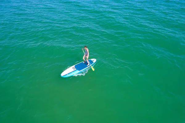 Aerial drone birds eye view of young woman exercising sup board in turquoise tropical clear waters — Stock Photo, Image