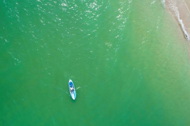 Tropik sahilde Sup tahtasında kürek çeken genç bir kadın. Paddle board ile aktif yaz tatilleri.