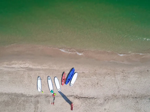 Groupe de panneaux de couleurs pour stand up paddle surf ou SUP couché sur la plage sur fond de vagues de mer le jour d'été — Photo