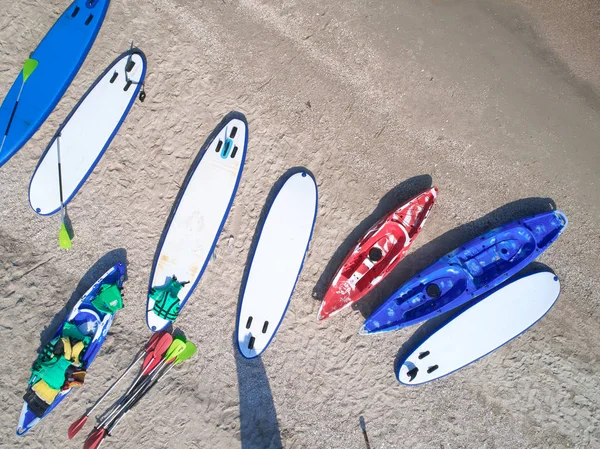 Groupe de panneaux de couleurs pour stand up paddle surf ou SUP couché sur la plage sur fond de vagues de mer le jour d'été — Photo