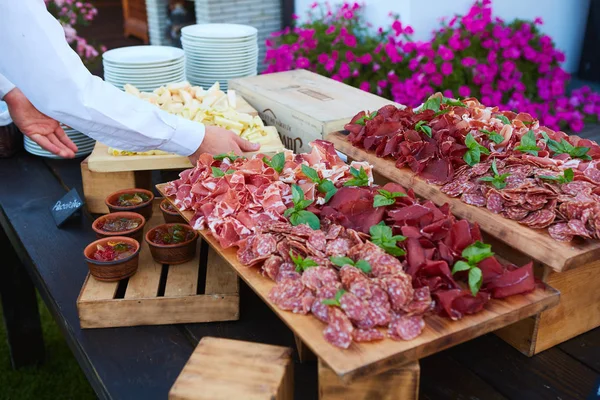 Placa y tabla con surtido de deliciosas carnes de delicatessen en la mesa —  Fotos de Stock