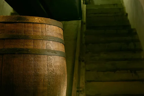 Barril de madeira sobre um fundo escuro, em uma oficina, em uma sala antiga. produção de barris para conhaque e vinho, em uma chave baixa — Fotografia de Stock