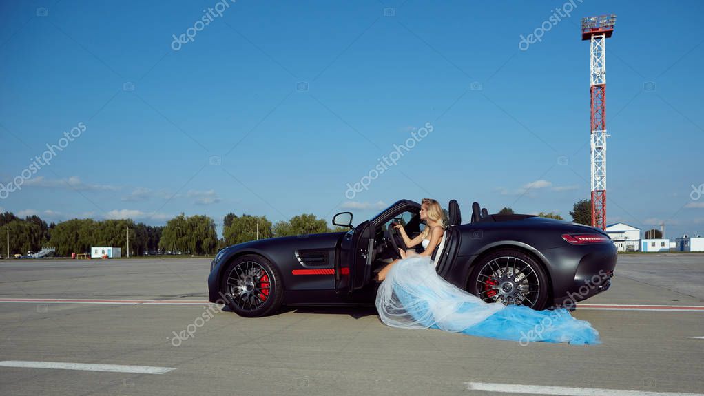 Красивая девушка позирует у спортивного автомобиля