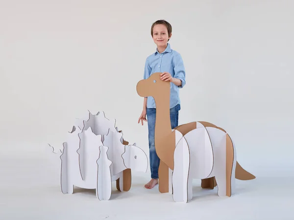 Pequeño niño soñador jugando con dinosaurios de cartón Brontosaurus y Ankylosaurus. Infancia. Fantasía, imaginación . — Foto de Stock