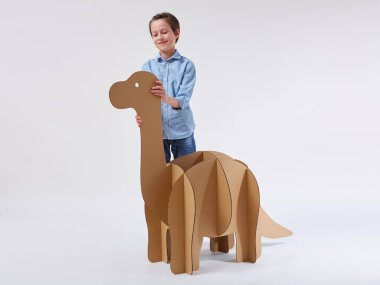 Küçük hayalperest çocuk, karton dinozor Brontosaurus 'la oynuyor. Çocukluk. Hayal gücü..