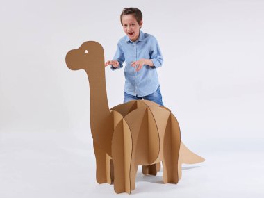 Küçük hayalperest çocuk, karton dinozor Brontosaurus 'la oynuyor. Çocukluk. Hayal gücü..