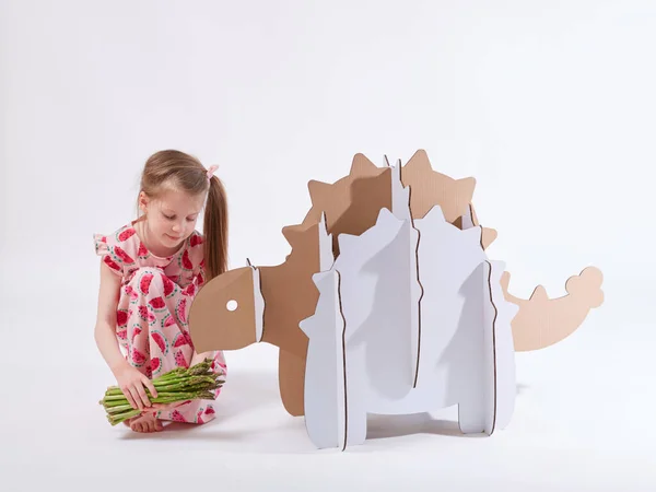 Petite fille rêveuse jouant avec un dinosaure en carton Ankylosaure. Enfance. Fantaisie, imagination . — Photo