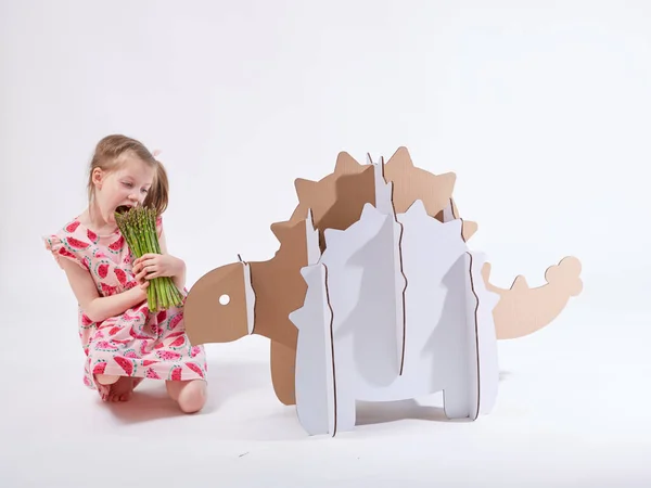 Kleine dromer meisje spelen met een kartonnen dinosaurus Ankylosaurus. Jeugd. Fantasie, verbeelding. — Stockfoto