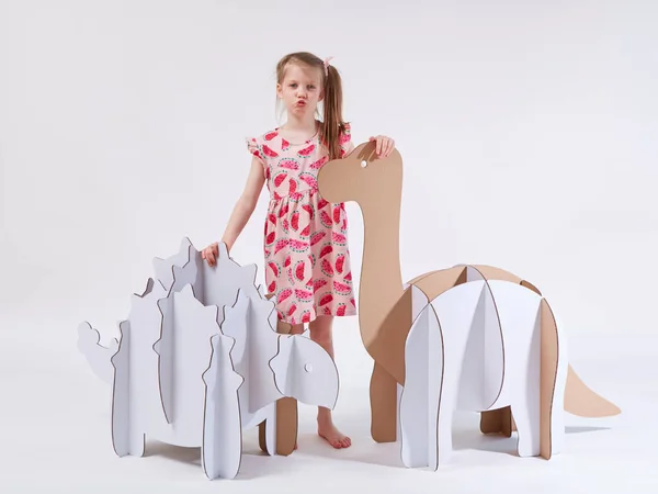 Little dreamer girl playing with a cardboard dinosaurs Brontosaurus and Ankylosaurus. Childhood. Fantasy, imagination — Stock Photo, Image