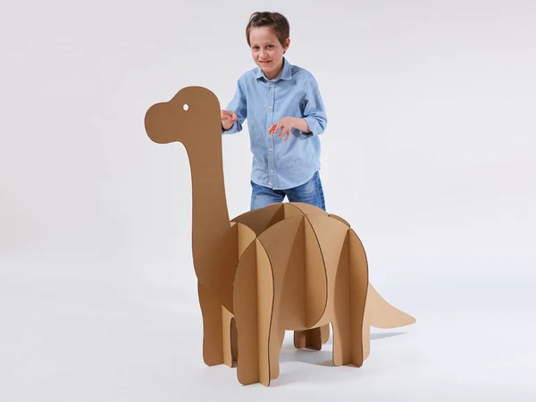Un niño soñador jugando con un dinosaurio de cartón Brontosaurus. Infancia. Fantasía, imaginación . —  Fotos de Stock