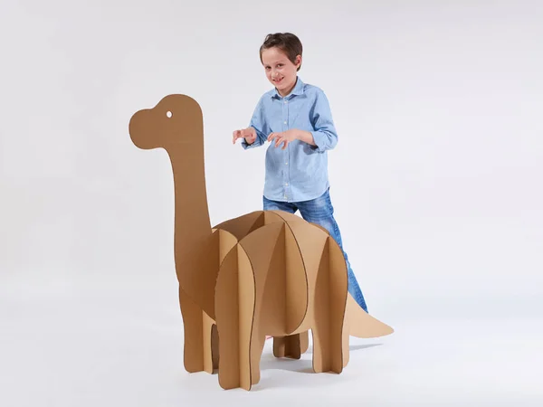 Un niño soñador jugando con un dinosaurio de cartón Brontosaurus. Infancia. Fantasía, imaginación . — Foto de Stock