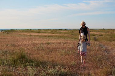 Gülümseyen anne ve güzel kız sahada eğleniyor. Mutlu bir kadının portresi kopya alanı olan küçük tatlı bir kızı sırtında taşıyor. Yazın çocuk ve annesinin portresi