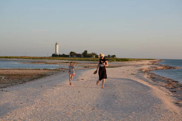 Mãe sorridente e bela filha se divertindo na praia. Retrato de mulher feliz dando um passeio de piggyback para a menina bonito com espaço de cópia. Retrato de criança e sua mãe durante o verão — Fotografia de Stock