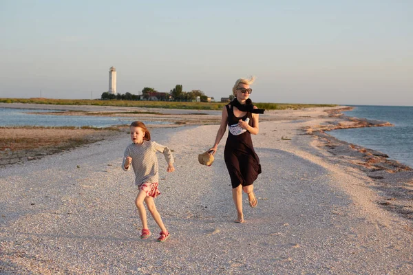 Χαμογελαστή μητέρα και όμορφη κόρη διασκεδάζουν στην παραλία. Πορτρέτο της ευτυχούς γυναίκας δίνοντας ένα piggyback βόλτα σε χαριτωμένο κοριτσάκι με χώρο αντίγραφο. Πορτρέτο του παιδιού και της μαμάς του το καλοκαίρι — Φωτογραφία Αρχείου