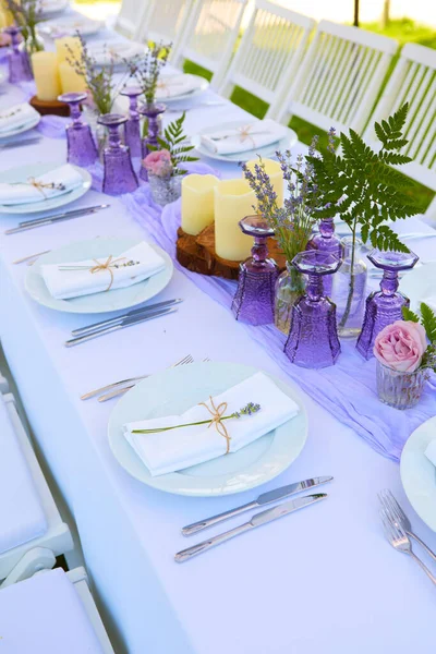 Elegant table setting for wedding engagement Easter dinner with white ceramic plates cotton napkin tied with twine lavender flowers candles. Provence style