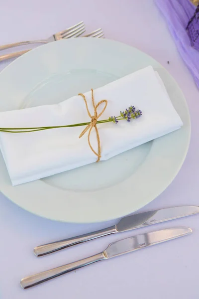 Beyaz seramik tabaklar, ipeksi lavanta çiçekli mumlarla bağlanmış pamuk peçeteyle Paskalya yemeği için şık bir masa. Provence biçimi — Stok fotoğraf