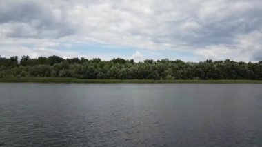 Nehrin güzel yaz manzarası. Nehir kıyısından görüntü. Öğlen. Rüzgar ağaçları karıştırıyor..