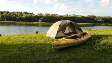 Çadırın ve nehir kıyısındaki sarı kanonun hızlandırılmış görüntüsü. Ufuktaki küçük bulutlar.