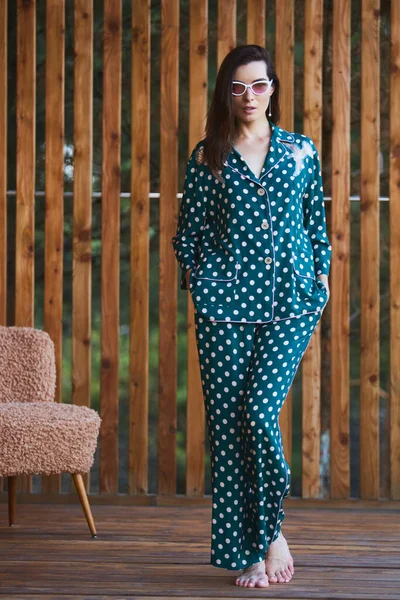 Mulher de pé em pijama de pijama com bolinhas no fundo de madeira em comprimento total. Modelo feminino caucasiano . — Fotografia de Stock