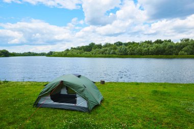 Göl kenarındaki ormanda yeşil bir çadırda.