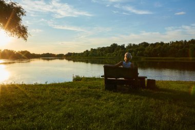 Güzel bir gün batımında bankta oturan kadın