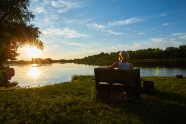 Güzel bir gün batımında bankta oturan kadın