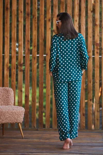 パジャマに身を包んだ女性は、木製の背景にポルカの点が長さいっぱいに並んでいます。白人女性モデル. — ストック写真