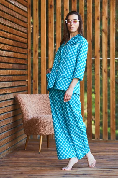 Frau im Pyjama-Pyjama mit Tupfen auf Holzgrund in voller Länge. Kaukasisches weibliches Modell. — Stockfoto