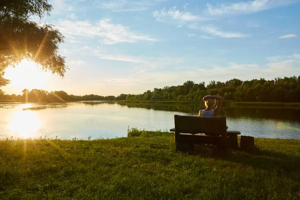 Frau sitzt auf Bank bei einem schönen Sonnenuntergang — Stockfoto