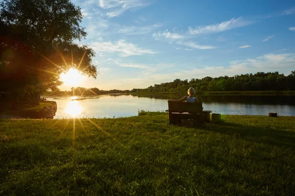 Donna seduta sul banco durante un bellissimo tramonto — Foto Stock