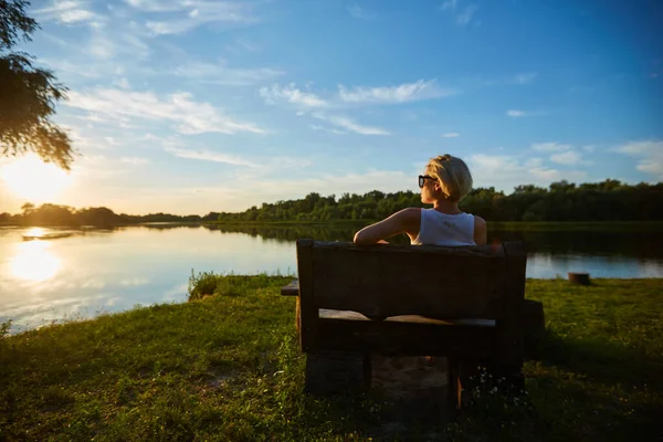 美しい夕日の中でベンチに座っている女 — ストック写真