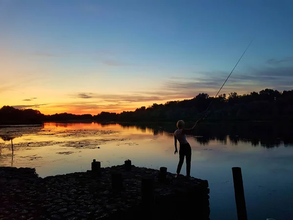 Young lady fishing on the river at sunset — Stock Photo, Image