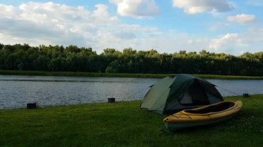 Çadırın ve nehir kıyısındaki sarı kanonun hızlandırılmış görüntüsü. Ufuktaki küçük bulutlar.