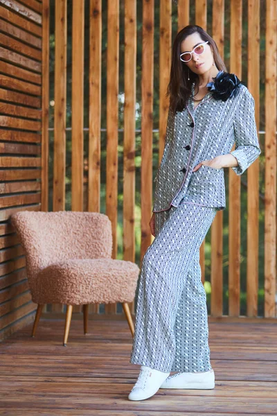 Jeune femme en pyjama se tient debout sur une terrasse en bois dans un pays tropical et regarde la jungle — Photo