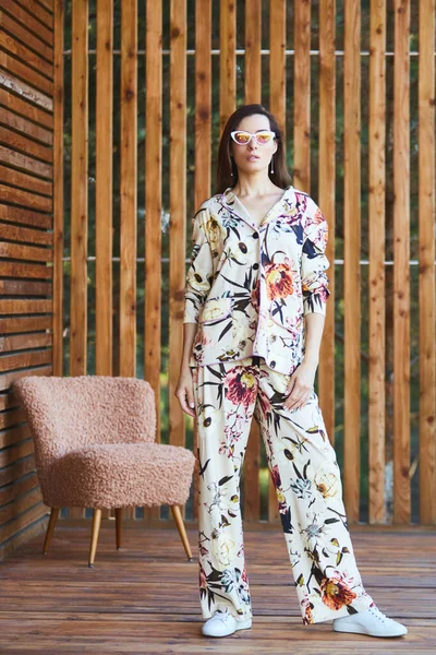 Junge stilvolle sexy Frau im Schlafanzug auf der Terrasse in tropischen Hotel, Palmen Hintergrund, lange schwarze Haare, Sonnenbrille, Ohrringe, Sonnenbrille. — Stockfoto