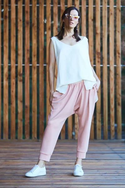 Femme en pantalon rose sur terrasse en bois. — Photo