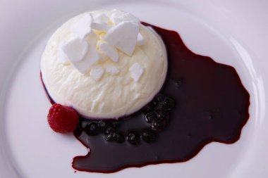 Panna cotta beyaz tabak ve böğürtlen sosu.