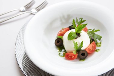 İtalyan domateslerinin üzerine beyaz yuvarlak top şeklinde İtalyan burrata peyniri konmuş geleneksel otantik yumuşak ve kremalı İtalyan burrata peyniri.