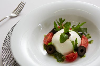İtalyan domateslerinin üzerine beyaz yuvarlak top şeklinde İtalyan burrata peyniri konmuş geleneksel otantik yumuşak ve kremalı İtalyan burrata peyniri.