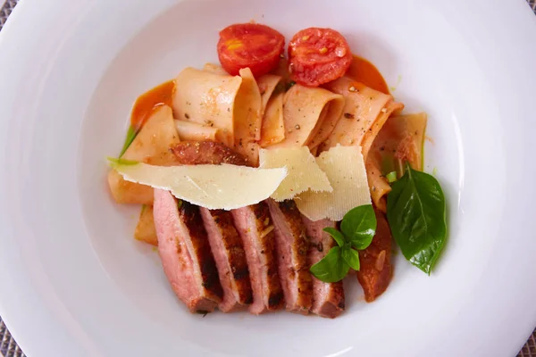 Vista de cerca de la pasta cocida y pechuga de pato en rodajas con salsa y parmesano con espacio para copiar. Dof poco profundo. — Foto de Stock