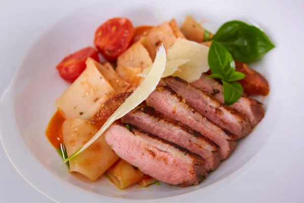 Close up view on cooked pasta and sliced duck breast with sauce and parmesan with copy space. Shallow dof. — Stock Photo, Image