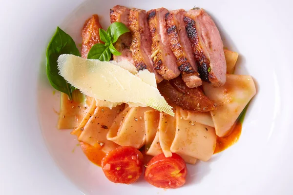 Close up view on cooked pasta and sliced duck breast with sauce and parmesan with copy space. Shallow dof. — Stock Photo, Image