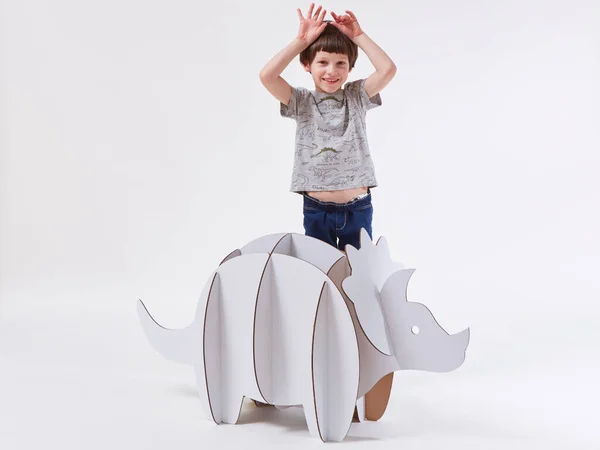 Little dreamer boy playing with a cardboard dinosaur Triceratops. Childhood. Fantasy, imagination. — Stock Photo, Image