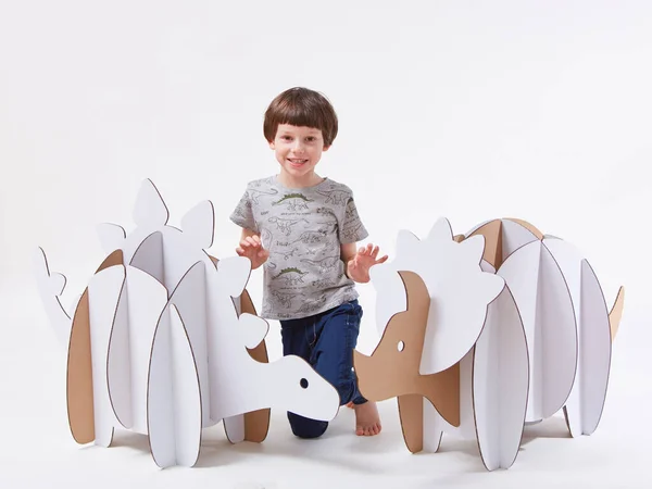 Pequeño niño soñador jugando con dinosaurios de cartón Triceratops y Stegosaurus. Infancia. Fantasía, imaginación. —  Fotos de Stock