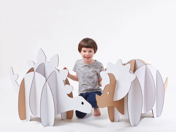 Pequeño niño soñador jugando con dinosaurios de cartón Triceratops y Stegosaurus. Infancia. Fantasía, imaginación. —  Fotos de Stock