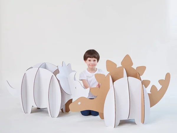 Pequeño niño soñador jugando con dinosaurios de cartón Triceratops y Stegosaurus. Infancia. Fantasía, imaginación. —  Fotos de Stock