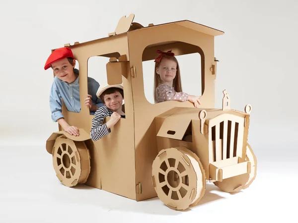 Enfants créatifs joue dans la maison de jeux de voiture en carton. — Photo
