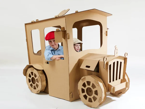 Creative children plays in cardboard car playhouse. — Stock Photo, Image