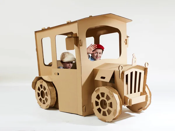 Los niños creativos juegan en la casita de cartón del coche. —  Fotos de Stock